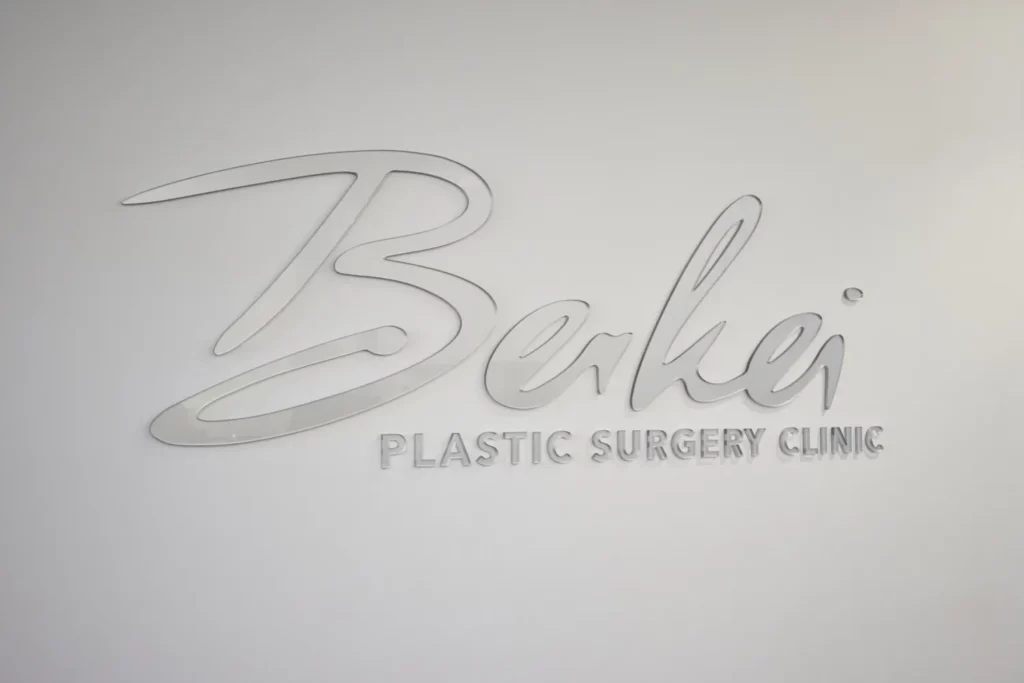 Silberner "Berkei Plastic Surgery Clinic" Schriftzug an einer Wand.