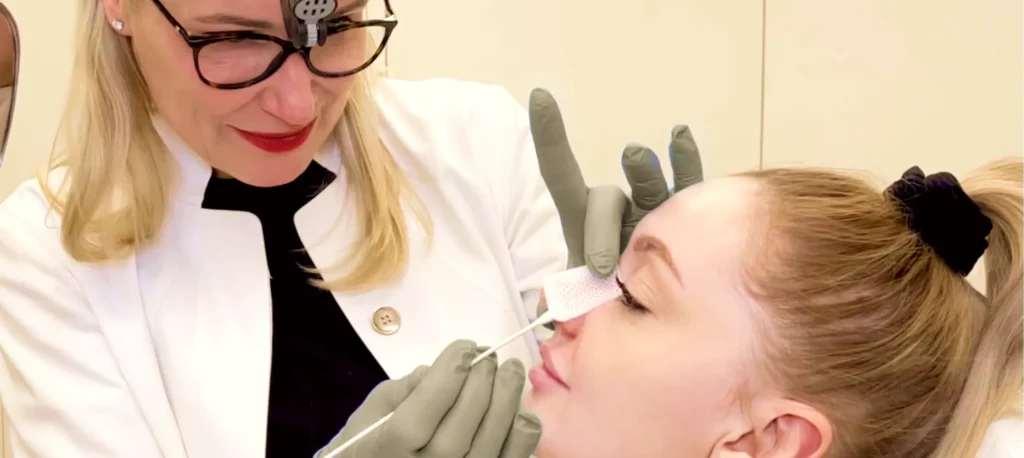 Aufnahme von Dr. Berkei, die die Nachuntersuchung der Nase bei einer Patientin durchführt.