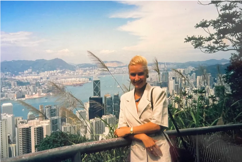 Glückliche Dr. Berkei, die an einem Geländer lehnt mit Aussicht über die Skyline von Hong Kong