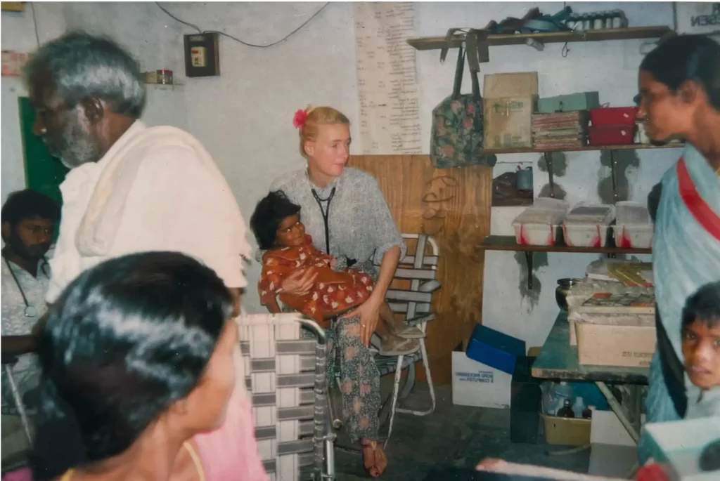 Aufnahme von Dr. Berkei in der Mitte mit einem kleinen Mädchen auf dem Schoß während ihrer Zeit in Indien. Um sie herum sind rechts und links noch weitere Personen.