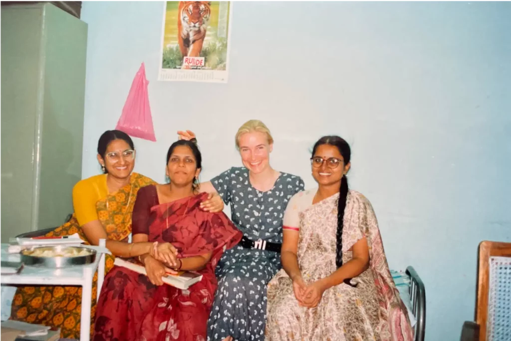Aufnahme von glücklicher Dr. Berkei und drei Kolleginnen auf einer Bettkante sitzend während ihrer Zeit in Indien.