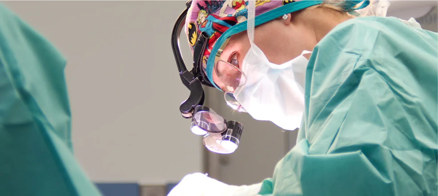 Aufnahme von Dr. Berkei hoch konzentriert während einer OP mit OP-Kleidung und Lupenbrille.