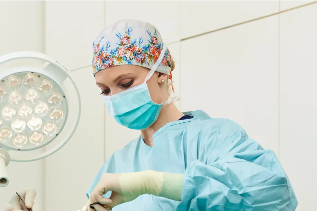 Aufnahme von konzentrierter Dr. Tosun im OP mit OP-Kleidung und einer geblümten OP-Mütze.