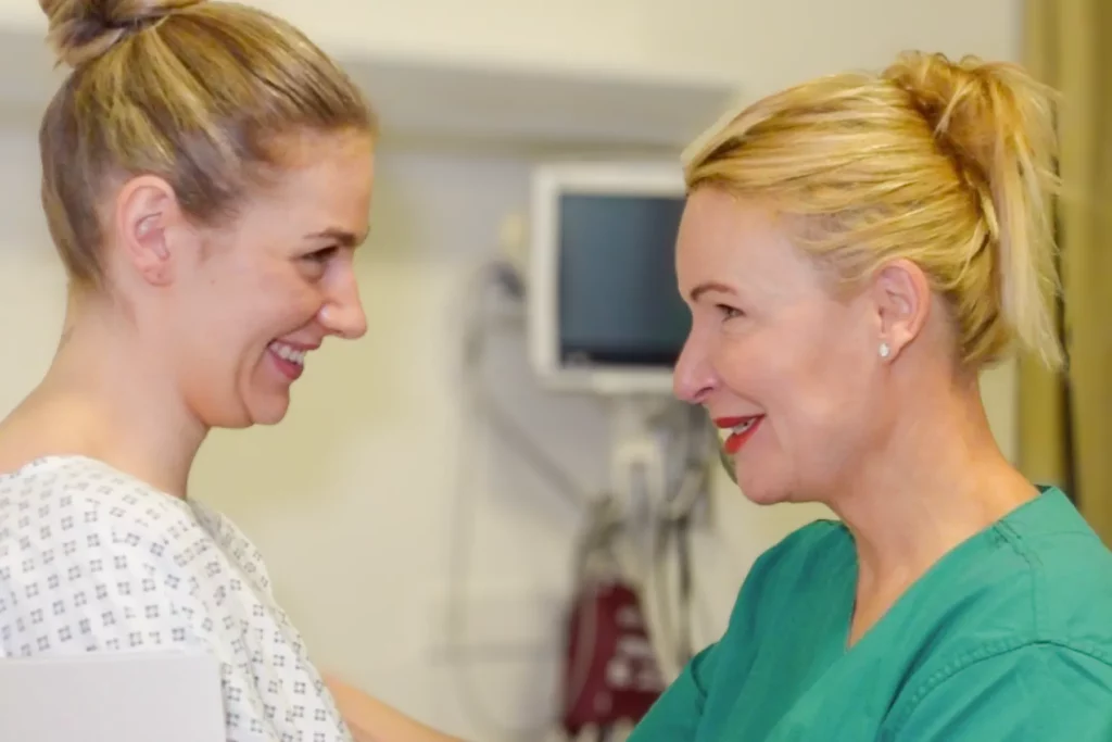 Aufnahme von Dr. Berkei und einer Patientin kurz vor der OP, die sich lächelnd gegenüber stehen.